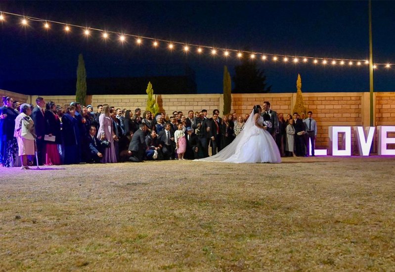 Recepción nocturna de boda con luces de bistró y invitados reunidos en el jardín de Sakura Metepec