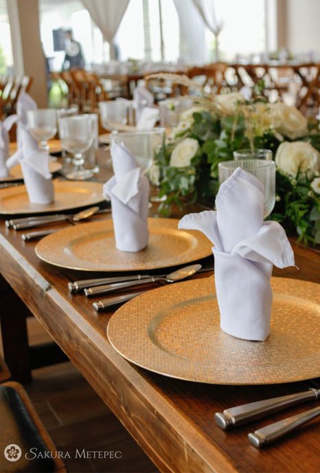 Montaje de mesa con platos base dorados y servilletas blancas para banquete de boda