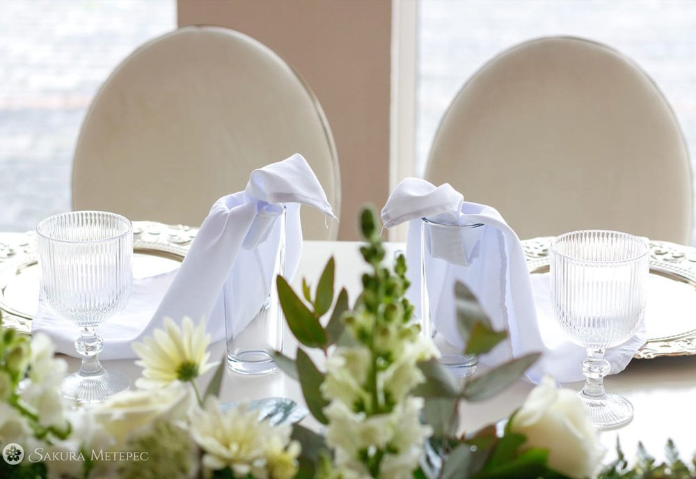 Centro de mesa floral blanco con servilletas y sillas vestidas para banquete de boda en Sakura Metepec