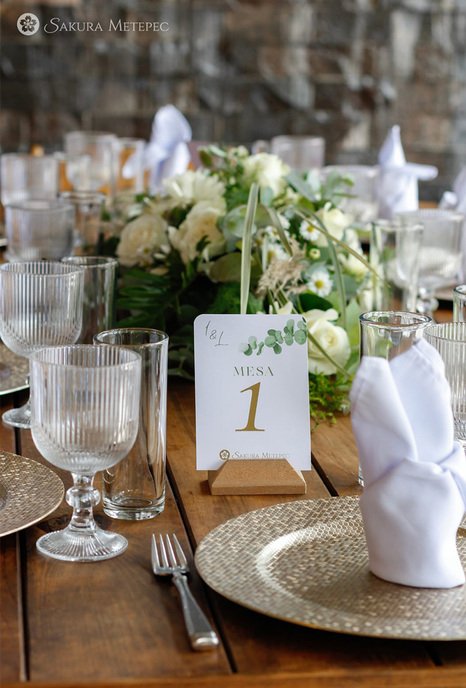Mesa de banquete con número de mesa y copas de cristal para recepción de boda