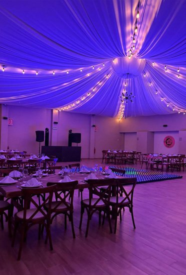 Salón Sakura con iluminación morada, pista LED y mesas montadas para fiesta de fin de año