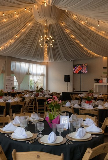 Salón Sakura con mesas redondas, centros florales y pantalla para evento corporativo