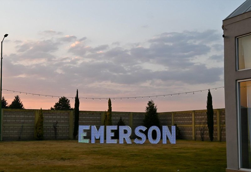 Letras gigantes EMERSON en el jardín de Sakura Metepec al atardecer durante evento de fin de año