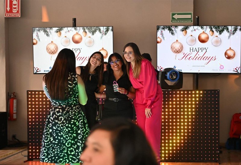 Colaboradoras celebrando posada empresarial frente a pantallas navideñas en el salón Sakura