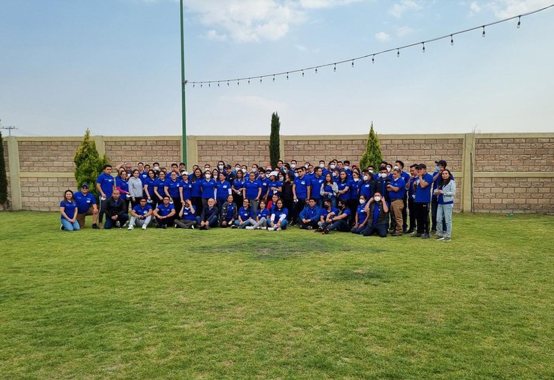 Foto grupal de equipo corporativo con uniforme azul en el jardín de Sakura Metepec