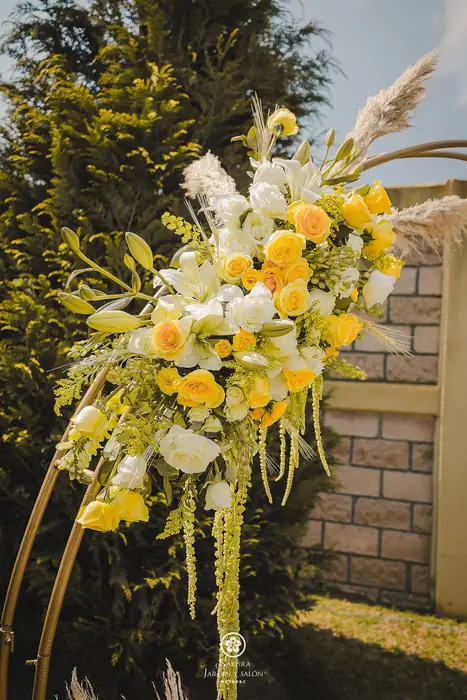 Arreglo floral de rosas amarillas y blancas en el arco de ceremonia en el jardín