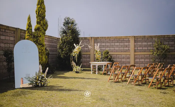 Montaje de ceremonia de boda en el jardín con arco floral, mesa para juez y espejo de bienvenida
