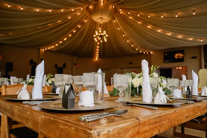 Mesa de banquete de boda con platos dorados, copas y recuerdos de novios en el salón Sakura