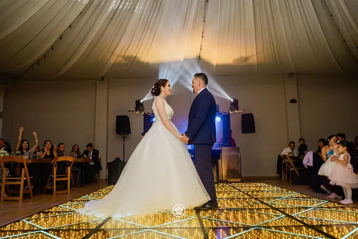 Primer baile de los novios sobre la pista LED bajo el techo entelado del salón Sakura en Metepec