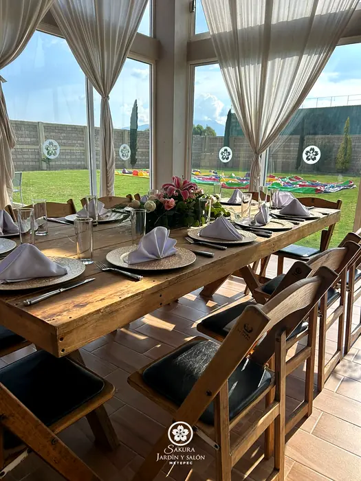 Mesa de madera junto al ventanal del salón con vista al jardín de Sakura Metepec